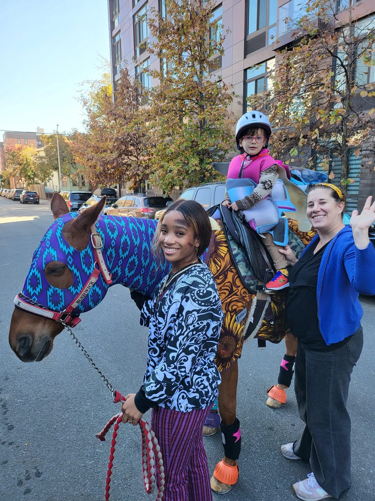 A child enjoying a pony ride with Brooklyn Equine staff